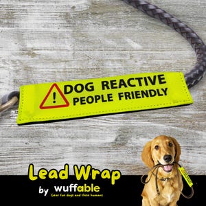 May include: A yellow dog lead wrap with the text "DOG REACTIVE PEOPLE FRIENDLY" and a warning symbol. The lead wrap is attached to a braided leather leash. The words "Lead Wrap" and "wuffable" are also visible.