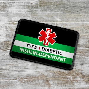 Może przedstawiać: Czarny i zielony znaczek ostrzegawczy medyczny z czerwonym symbolem gwiazdy życia i tekstem "TYPE 1 DIABETIC INSULIN-DEPENDENT".
