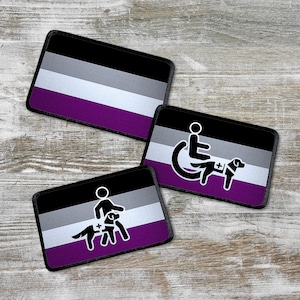 Könnte beinhalten: Drei schwarze und weiße Patches mit den Farben der asexuellen Pride-Flagge. Die Patches zeigen eine Person im Rollstuhl mit einem Assistenzhund, eine Person mit einem Assistenzhund und die asexuelle Pride-Flagge.