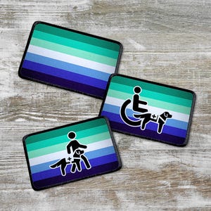 May include: Three embroidered patches with a teal, blue and white striped background. The patches feature a person in a wheelchair with a service dog, a person with a service dog, and a plain striped patch.