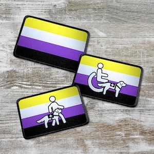 Op de afbeelding: Drie geborduurde patches met de kleuren van de non-binaire pride-vlag: paars, wit en geel. De patches tonen een persoon in een rolstoel met een hulphond, een persoon met een hulphond en de non-binaire pride-vlag.
