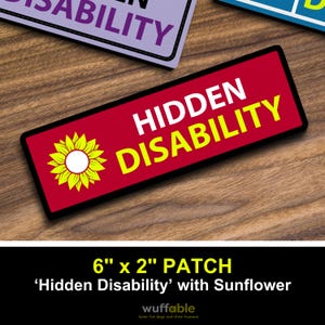 May include: A red rectangular patch with the words "HIDDEN DISABILITY" in white and yellow. A yellow sunflower is on the left. The patch is 15 cm x 5 cm.