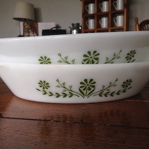 Peut inclure: Deux plats à four en céramique blanche avec des motifs floraux verts. Les plats sont empilés l'un sur l'autre.