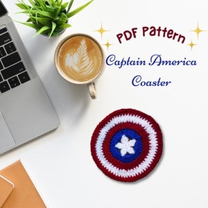 May include: A crocheted Captain America coaster in red, white, and blue, featuring a star in the center. The coaster is round and sits on a white surface. Text on the image reads "PDF Pattern Captain America Coaster."