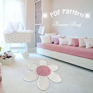 May include: A white crocheted flower rug with a pink center. The rug is in a nursery with a white crib and a pink couch.