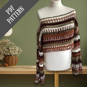 May include: A crochet off-the-shoulder top in shades of brown, white, and olive green is displayed on a mannequin. The top features a unique openwork design and long sleeves. The words "PDF PATTERN" are in the upper left corner.