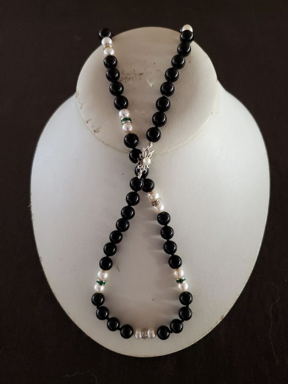 Onyx, pearls, 18k diamond and emerald roundelle