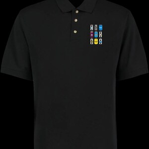 Puede incluir: Polo negro con tapeta de tres botones y un peque&ntilde;o gr&aacute;fico colorido de latas de bebidas en el pecho izquierdo. El gr&aacute;fico presenta varios colores y dise&ntilde;os, agregando un toque de detalle a la camisa.
