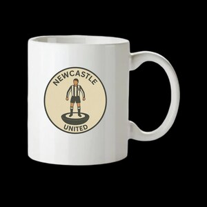 Peut inclure: Mug en c&eacute;ramique blanche avec le logo de Newcastle United. Le logo est un design circulaire avec les mots "Newcastle United" et un joueur de football en rayures noires et blanches. La tasse a une anse incurv&eacute;e.