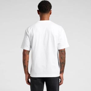 K&ouml;nnte beinhalten: Ein wei&szlig;es T-Shirt mit kurzen &Auml;rmeln. Die R&uuml;ckansicht zeigt das schlichte Design und die Passform des Shirts. Der Stoff ist weich und blickdicht. Das Model tr&auml;gt eine schwarze Hose. Der Hintergrund ist hellgrau.