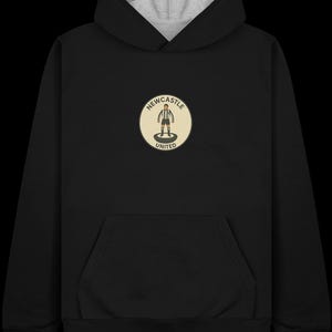 Peut inclure: Sweat &agrave; capuche noir avec une capuche doubl&eacute;e grise et une poche kangourou. L'avant pr&eacute;sente un &eacute;cusson circulaire avec le texte "Newcastle United" et un joueur de football stylis&eacute;.
