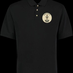 Peut inclure: Polo noir &agrave; manches courtes avec une patte de boutonnage &agrave; trois boutons. Il pr&eacute;sente un &eacute;cusson circulaire sur la poitrine avec le texte "Newcastle United" et une figurine de joueur de football.