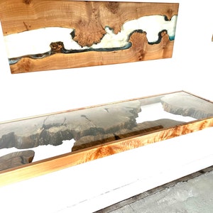May include: A wooden shelf with a glass top, featuring a natural wood grain and a clear epoxy resin pour. The shelf is mounted to a white wall.