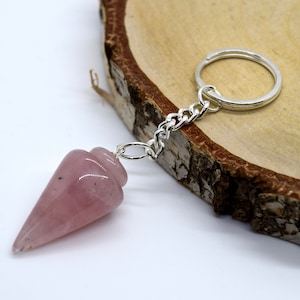 May include: A pink rose quartz crystal pendulum on a silver chain with a key ring.