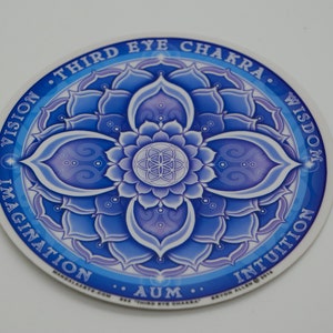 Pode incluir: Um adesivo mandala azul e branco com as palavras "Terceiro Olho Chakra" e "Aum" no centro. O mandala apresenta um desenho de flor com quatro pétalas e as palavras "Visão", "Imaginação", "Intuição" e "Sabedoria" ao redor da borda exterior.
