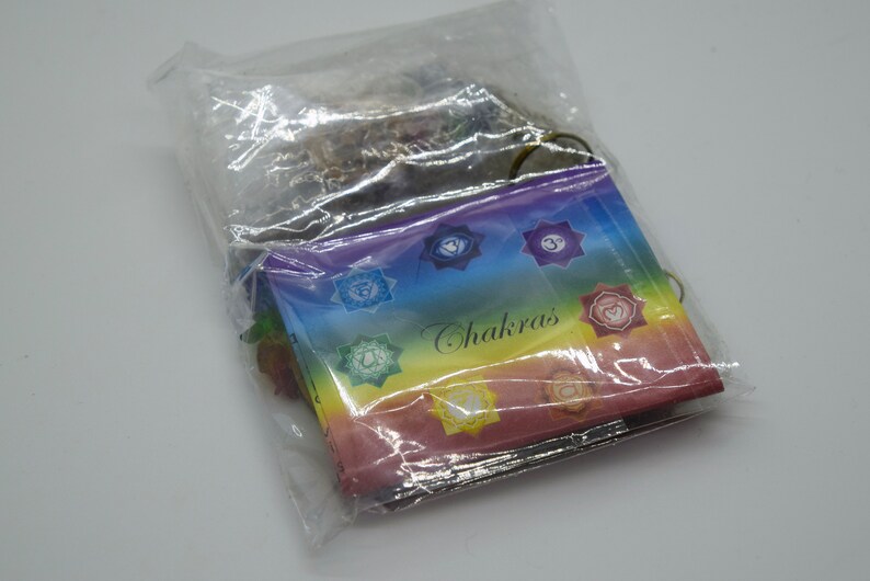 May include: A plastic bag containing a set of seven chakra cards. The cards are rainbow colored and feature symbols and the word "Chakras".