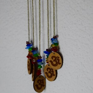 May include: Five gold chains with colorful glass beads and wooden pendants with the Om symbol.