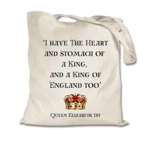 May include: A white tote bag featuring a quote from Queen Elizabeth I: 'I have the heart and stomach of a king, and a king of England too'. The quote is printed in black text and is centred on the bag. A gold crown with red jewels is below the quote. The words 'Queen Elizabeth 1st' are printed in black text below the crown.