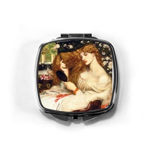 Könnte beinhalten: Ein quadratischer, silberfarbener Kompaktspiegel mit einem präraffaelitischen Gemälde. Das Kunstwerk zeigt eine Frau mit langen, roten Haaren, die in einen Handspiegel blickt. Das Bild zeigt eine Frau in einem weißen Kleid, mit floralem Hintergrund und einem Blick aus dem Fenster.