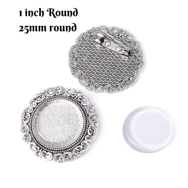 May include: Silver-toned round brooch components with decorative edges. The image includes a brooch back with a pin, a bezel, and a clear glass cabochon. Text reads "1 inch Round" and "25mm round".