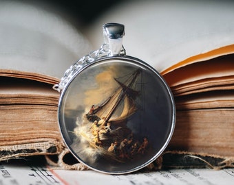 Op de afbeelding: Een zilveren ketting met een ronde glazen cameo met een schilderij van een schip dat door een stormachtige zee vaart.