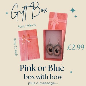 May include: Pink gift box with a bow, containing a pair of silver earrings with black silhouette designs. The box is 1.9 inches wide and 3.5 inches tall. Text on the image reads "Gift Box" and "Pink or Blue box with bow plus a message..."