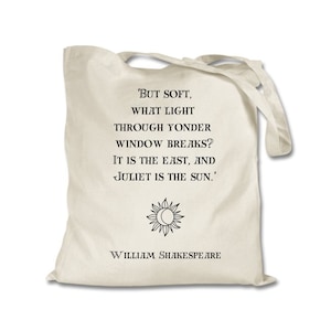 May include: A beige tote bag with a black quote from William Shakespeare: 'But soft, what light through yonder window breaks? It is the east, and Juliet is the sun.'  The quote is centered on the bag with a sun and moon symbol below it.