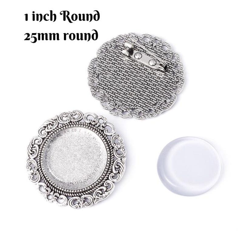 May include: A set of three silver-toned metal round 1 inch (25 mm) blank cabochon settings with a decorative filigree design. The settings are for making jewelry or crafts. One setting has a pin back.