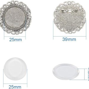 May include: Two silver-toned metal round frames with a decorative design. The larger frame measures 39 mm in diameter and has a pin back. The smaller frame measures 25 mm in diameter and has a flat back. Two clear glass circles, one measuring 25 mm in diameter and the other measuring 4.5 mm in diameter.