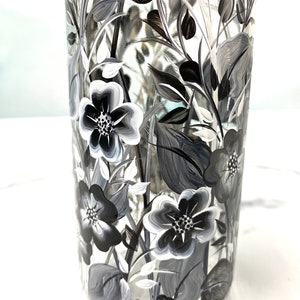 K&ouml;nnte beinhalten: Eine klare Glasvase mit einem schwarz-wei&szlig;en Blumenmuster, das auf die Seite gemalt ist. Die Blumen sind stilisiert und haben einen einfachen, eleganten Look.