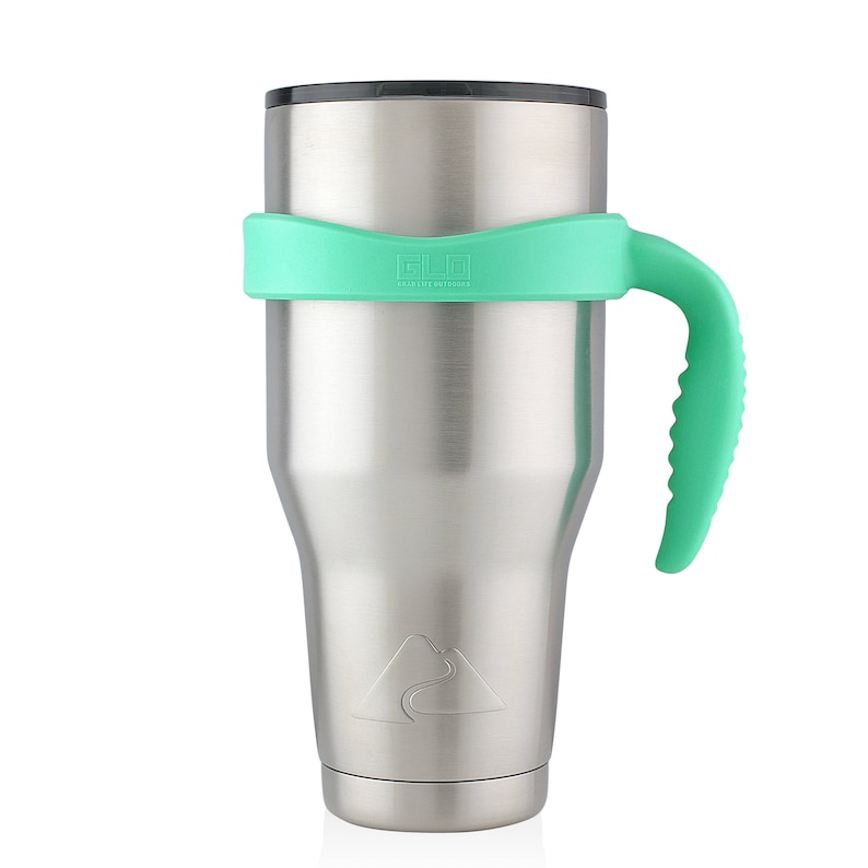 May include: A stainless steel tumbler with a green silicone handle and lid. The tumbler has a mountain range design and the text "Ello" on the lid.