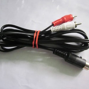 May include: Black audio cable with red and white RCA connectors and a black DIN connector. The cable is bundled with an orange rubber band. The connectors are visible against a white background.