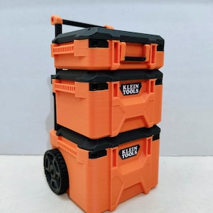 May include: An orange and black rolling tool box with the "KLEIN TOOLS" logo. The tool box is stacked in three sections, with a handle and wheels for easy transport. The tool box is made of plastic.