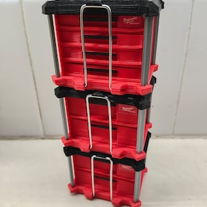 May include: Three red and black stackable tool boxes with a metal handle. The boxes are labeled "Milwaukee" and "Packout".