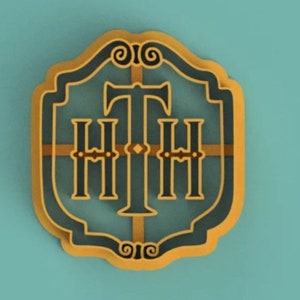 Op de afbeelding: Een goudkleurig, versierd, schildvormig logo met de letters "HHH" in zwart en een gestileerd kruis in het midden. Het logo bevindt zich op een blauwe achtergrond.