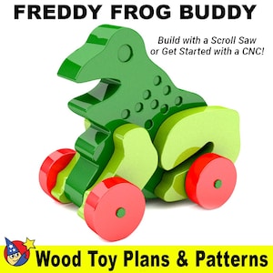 Könnte beinhalten: Ein grünes und gelbes Holzspielzeug-Frosch mit roten Rädern. Das Spielzeug ist so konzipiert, dass es mit einer Laubsäge oder einer CNC-Maschine gebaut werden kann. Der Text "FREDDY FROG BUDDY" befindet sich oben im Bild. Der Text "Build with a Scroll Saw or Get Started with a CNC!" befindet sich in der oberen rechten Ecke des Bildes. Der Text "Wood Toy Plans & Patterns" befindet sich unten im Bild.