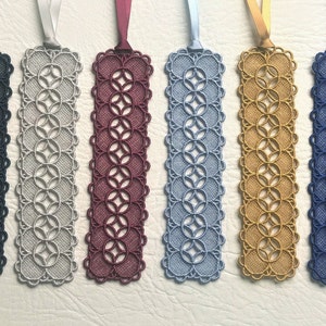 May include: Six handmade bookmarks with a delicate lace design. The bookmarks are in various colours, including navy blue, silver, burgundy, light blue, gold, and dark blue.