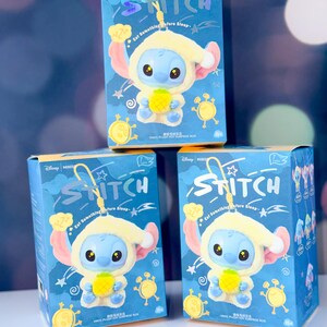 May include: Three blue boxes featuring the character Stitch from Disney's Lilo & Stitch. Each box displays a Stitch figure wearing a yellow hooded outfit and holding a pineapple. The boxes have the word "Stitch" and the text "Eat Something Before Sleep".