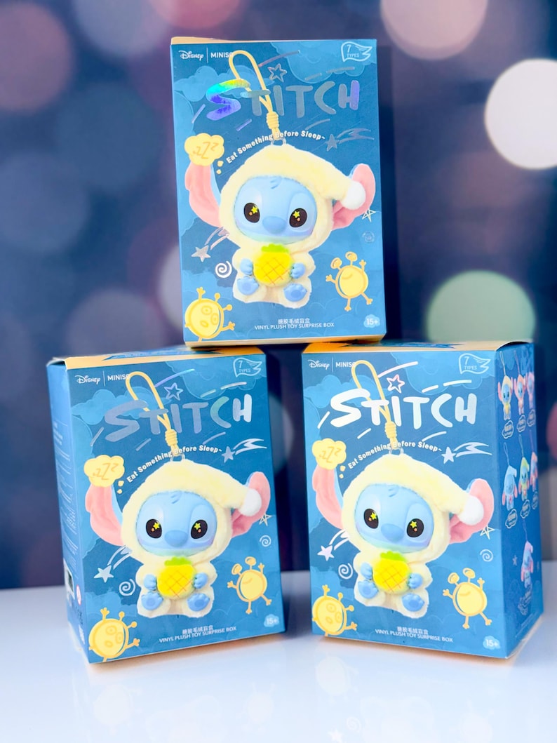 May include: Three blue boxes featuring the character Stitch from Disney's Lilo & Stitch. Each box displays a Stitch figure wearing a yellow hooded outfit and holding a pineapple. The boxes have the word "Stitch" and the text "Eat Something Before Sleep".