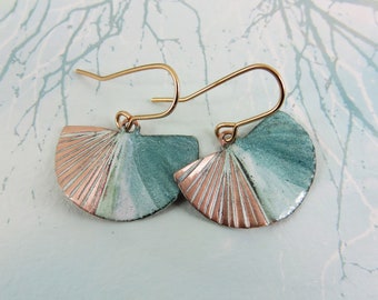 May include: A pair of gold earrings with a fan-shaped design. The earrings are made of metal and have a green and white enamel finish with a copper accent.