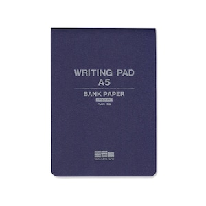 May include: A blue writing pad with the text "WRITING PAD A5 BANK PAPER 100 SHEETS PLAIN" and the logo "YAMAMOTO PAPER" printed on the front.