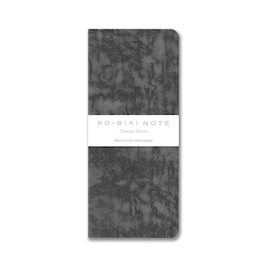 May include: A dark gray notebook with a textured surface. The notebook has a white band across the middle with the text "RO-BIKI NOTE Texture Series" and "Blank and Free writing 60pgs". The notebook is rectangular and has rounded corners.