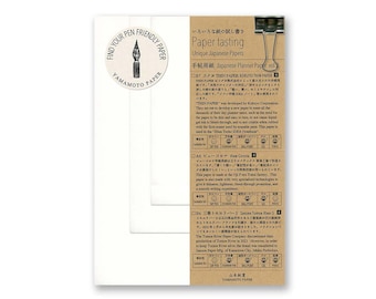 Puede incluir: Un primer plano de la parte posterior de un paquete de papel para planificador japonés. El paquete es marrón con texto blanco y una pequeña ilustración de una pluma. El texto en el paquete dice "Paper tasting Unique Japanese Papers" y "Japanese Planner Paper vol."