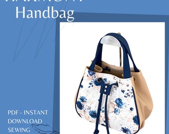 May include: A white handbag with a blue floral print and a navy blue top handle and drawstring. The bag has a beige bottom and a white background with blue flowers.
