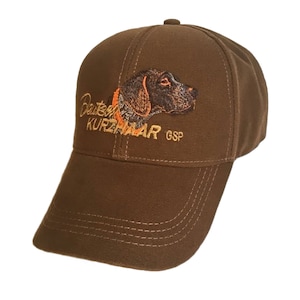 May include: Brown baseball cap with an embroidered German Shorthaired Pointer dog and the text "Deutscher Kurzhaar GSP".