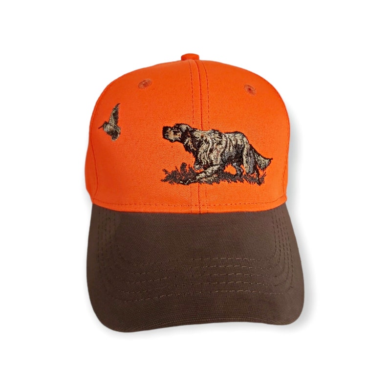 May include: Orange and brown baseball cap with an embroidered image of a dog and a bird.