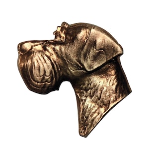 May include: A bronze-colored sculpture of a dog's head, showcasing detailed features like the snout, ear, and neck. The sculpture has a textured surface, and the dog's head is angled slightly upward. The overall design is realistic and detailed.