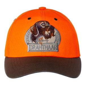 May include: Orange and brown baseball cap with an embroidered patch of a German Wirehaired Pointer dog. The patch says "German Wirehaired Pointer" and "Drahthaar".