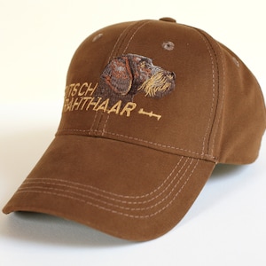 Puede incluir: Gorra de béisbol marrón con un perro Braco Alemán de Pelo Duro bordado y el texto "Deutscher Drahthaar" en hilo dorado.