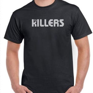 May include: A black t-shirt with a white pixelated graphic of "the KILLERS" printed on the front.